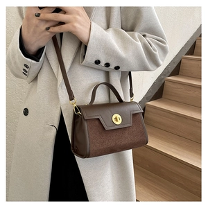 Detail of vintage brown frosted leather crossbody bag with golden round metal lock