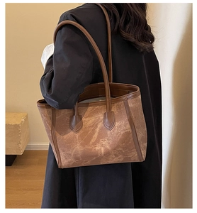 Brown leather tote bag worn by a model in a commute setting showing texture and drape