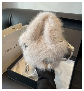 Detailed shot of soft beige faux fur bucket bag in a black premium gift box setting