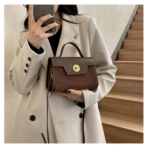 Close-up of matte brown patchwork handbag with gold rotary lock and leather strap
