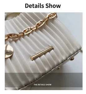 Détail du sac seau plissé ivoire avec bandoulière en chaîne dorée et finitions métalliques