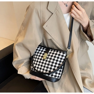 Détail du sac seau à damier avec boucle dorée et bandoulière en cuir noir