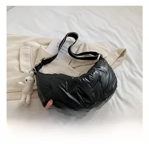 Detail der schwarzen gesteppten Halbmond-Tasche mit glänzendem Finish und Hasenanhänger