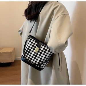 Détail du sac seau à carreaux noir et blanc avec texture tissée et fermoir en métal doré