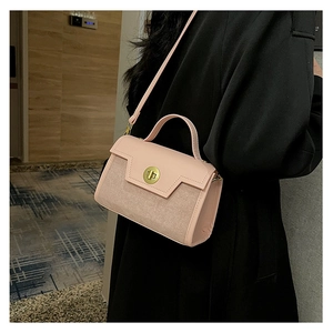 Detail of pink matte leather crossbody bag with golden round swivel lock on black coat