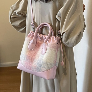 Sac seau en cuir rose et tweed à carreaux porté avec un trench-coat kaki très élégant