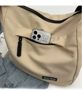 Detailed view of the front zipper pocket on a beige tote showing storage for a smartphone