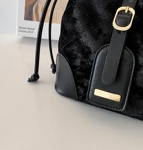 Détail du sac seau en velours noir montrant la texture matelassée et le fermoir doré