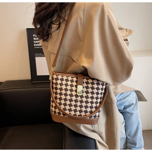 Détail du sac seau à damier marron avec garniture en cuir et boucle de verrouillage en métal
