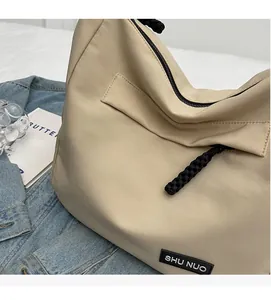Detail of beige nylon tote bag featuring durable fabric texture and woven zipper pullers
