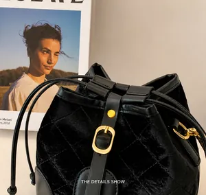 Détails rapprochés du sac seau en velours noir avec quincaillerie dorée et matelassage