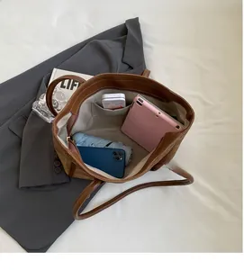 Top-down view of a spacious brown leather tote bag with internal pocket and daily items