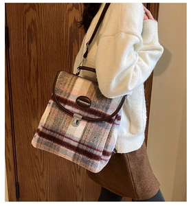 Detail of plaid tweed backpack with brown leather trim and silver metal buckle closure
