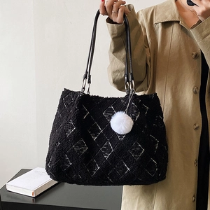Fuzzy black lamb wool tote bag with white grid patterns and a plush pompom charm