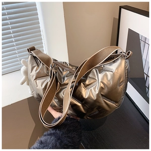 Detailansicht der gesteppten Halbmondtasche in Bronze-Metallic mit Plüschanhänger