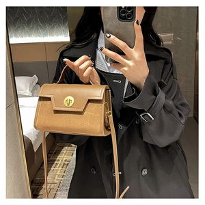 Detail of brown leather handbag with gold turn-lock closure and frosted patchwork finish