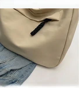 Close-up of beige nylon tote bag featuring SHU NUO label and black braided zipper detail