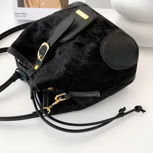 Détail du sac seau en velours noir montrant la texture matelassée et les boucles dorées