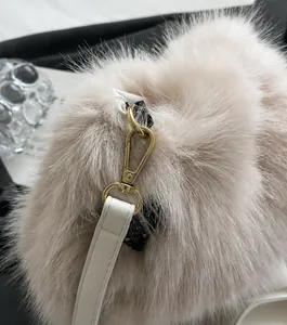 Close-up of golden metal hooks and soft plush faux fur texture on the luxury bucket bag