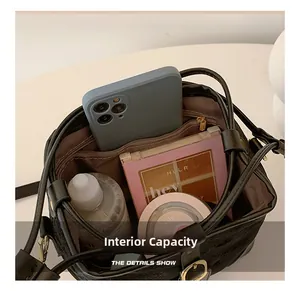 Capacité interne du sac seau en cuir noir montrant le compartiment et la poche zippée