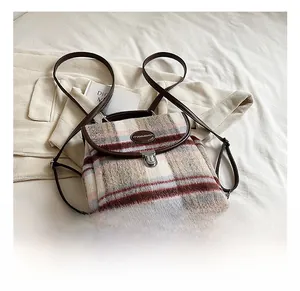 Detail of plaid tweed backpack featuring brown leather straps and silver metal buckle lock