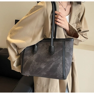 Detail of grey textured large tote bag styled with a beige trench coat for a commute look