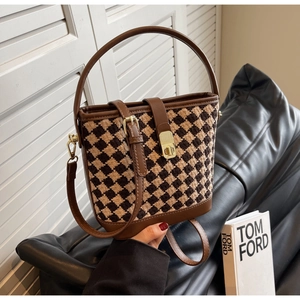 Détail d'un sac seau rétro en tweed bicolore avec fermoir doré et bordure cuir