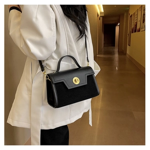 Detail of black matte suede and leather crossbody bag with golden cylinder rotating lock