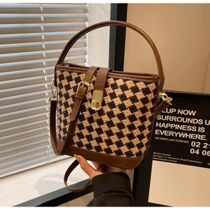 Détail d'un sac seau en cuir marron avec motif pied-de-poule et fermoir en métal doré