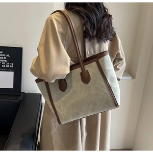 Detail of grey-green suede tote bag with brown leather handles on shoulder for daily commute