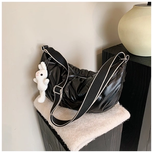 Detail einer schwarzen Stepptasche mit weißem Hasenanhänger und breitem Schultergurt