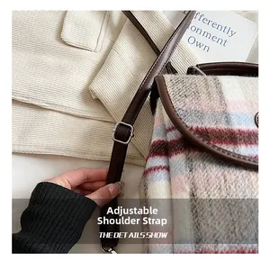 Detail shot of adjustable brown leather shoulder strap with silver buckle on plaid bag