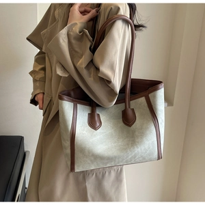 Model wearing a vintage faux suede tote bag in grey-green with dark brown leather straps