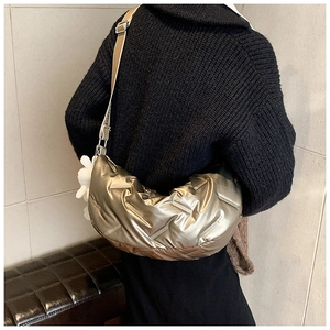 Detail der gesteppten Metallic-Damentasche mit verstellbarem Riemen und Blumenanhänger