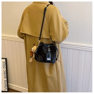 Détail du sac seau noir matelassé avec dorures et charmant porte-clés ours en peluche