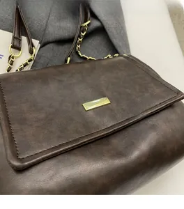 Detail of dark brown leather tote featuring vintage texture and gold metallic hardware
