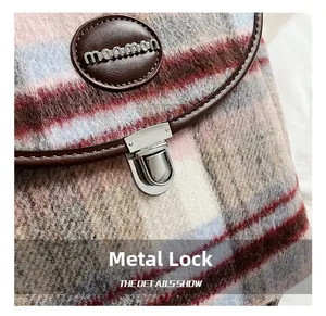 Detail of colorful plaid tweed fabric with silver metal twist lock and leather brand patch