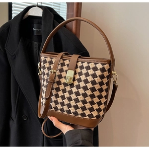 Détail du sac seau vintage à motif pied-de-poule avec bordure en cuir et boucle dorée