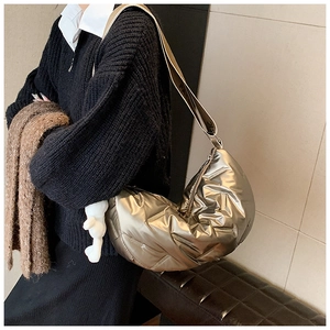 Detail der champagnerfarbenen Stepptasche mit breitem Gurt und Plüschbär-Anhänger