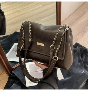 Detail of vintage dark brown tote bag featuring gold metal plate and chain strap