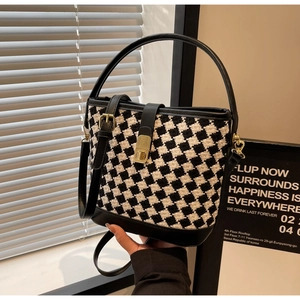 Détail du sac seau en pied-de-poule avec bordure en cuir et fermoir doré rotatif