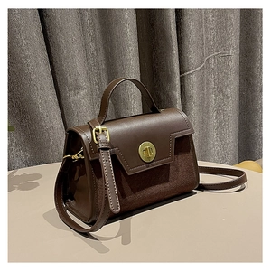 Detail view of deep brown vintage matte leather bag with golden twist lock on light table