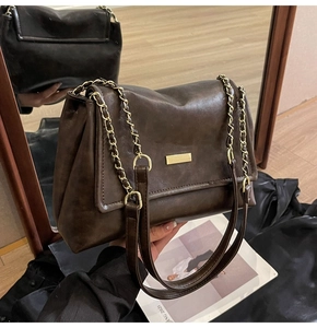 Detailed close-up of dark brown oil wax leather bag with vintage gold chain strap