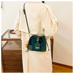 Détail du sac seau en velours vert foncé avec matelassage et breloque ours mignon