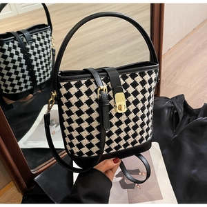 Détail du sac seau en tweed à carreaux avec fermoir doré et garniture en cuir sur miroir