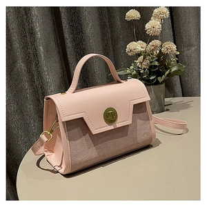 Close-up of pink shoulder bag with matte texture, golden metal lock, and stitching detail