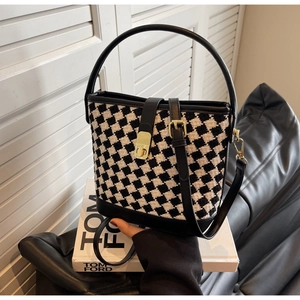 Détail du sac seau à carreaux avec poignée en cuir noir et fermoir à boucle dorée