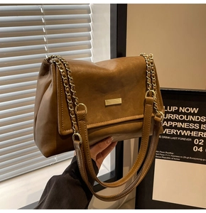 Detail of caramel brown leather tote bag with gold chain strap and metallic buckle