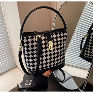 Détail de la texture pied-de-poule et garniture en cuir noir du sac seau bandoulière