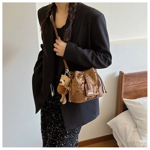 Détail d'un sac seau en velours marron avec surpiqûres et pendentif d'ours